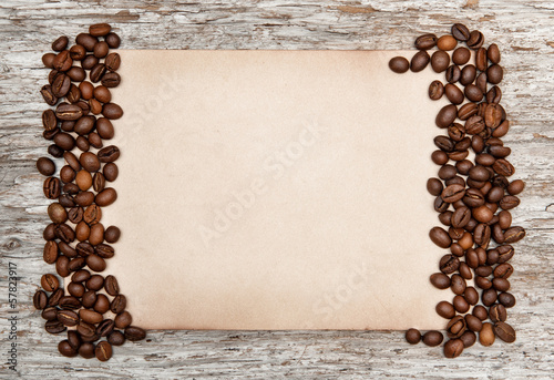 Aged sheet of paper with coffee beans on the old wood