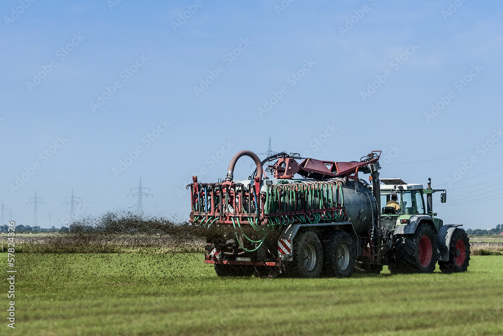 Fototapeta premium Landwirtschaft Traktor mit großem Hänger beim Düngen
