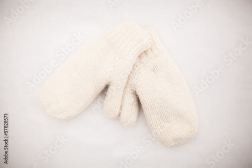 Soft warm knitted mittens on the white snow