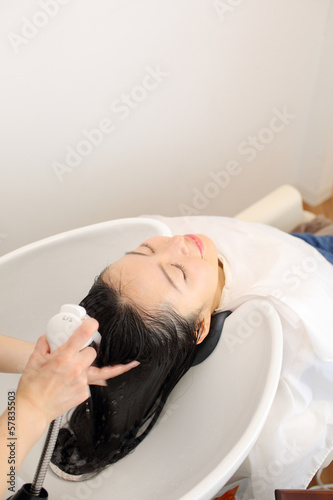 シャンプー台で髪を洗う女性