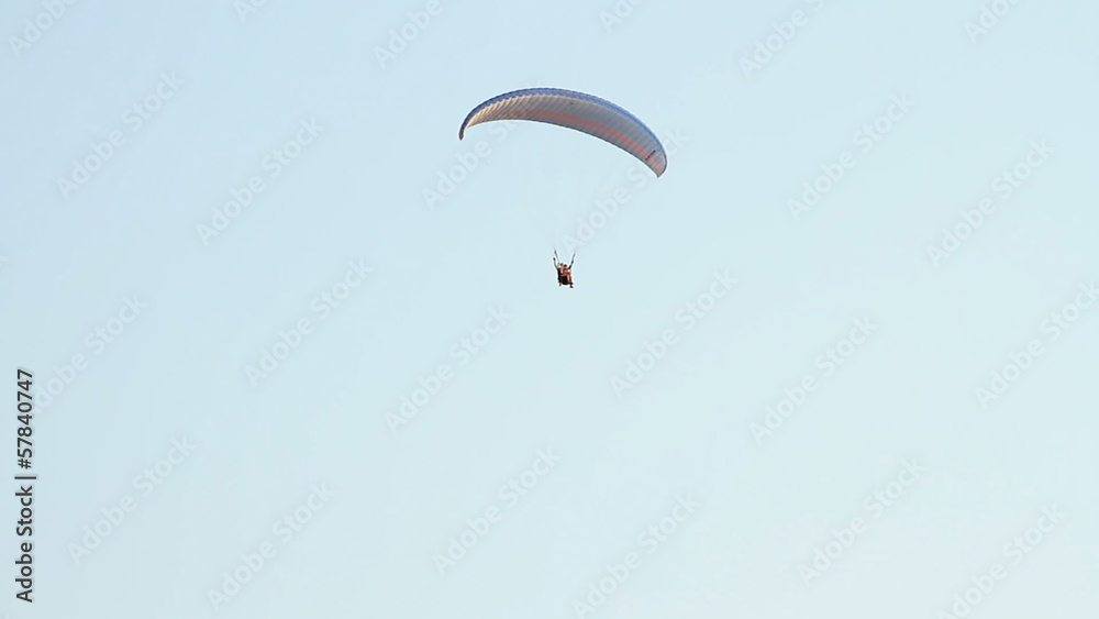 Paragliding over the mountains against clear blue sky Paragliding over the mountains against clear blue sky