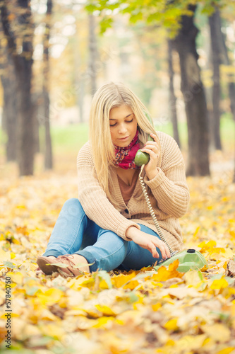 young woman talking on vintage phone in autumn park