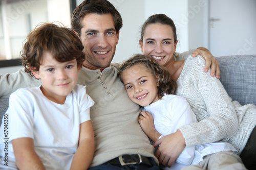 Happy family of four relaxing in sofa