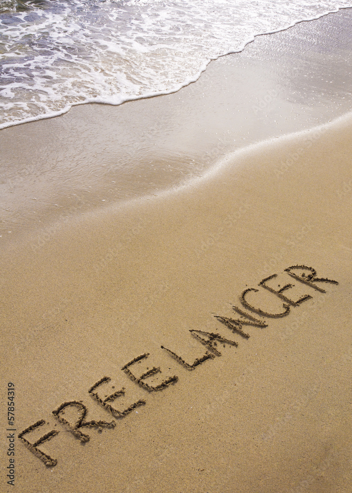 Fototapeta premium Word FREELANCER written in sand, on a beautiful beach