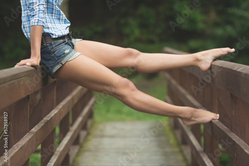 Stretched legs of woman sitting on bridge photo