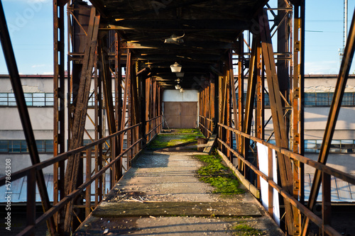 Closed metal door at the end of old rusty bridge