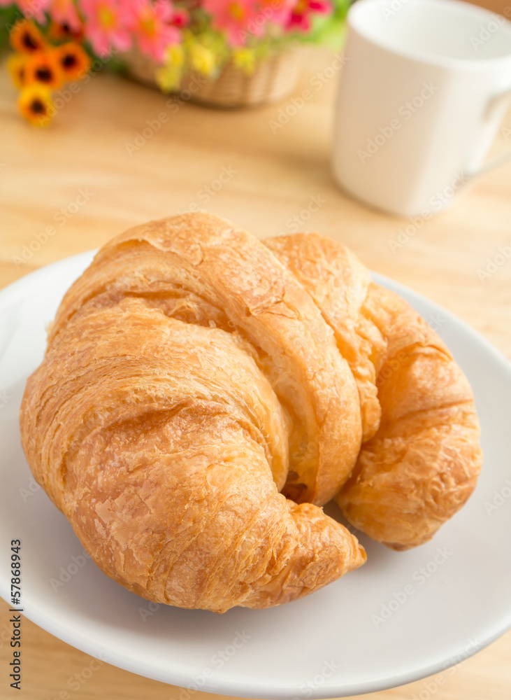 Closeup of a croissant with coffee cup