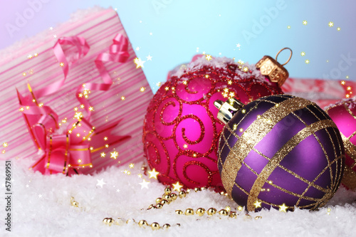 beautiful Christmas balls and gifts on snow on bright photo