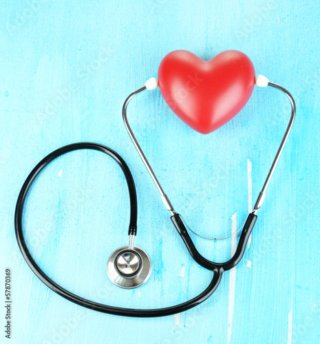 Stethoscope and heart on wooden table close-up