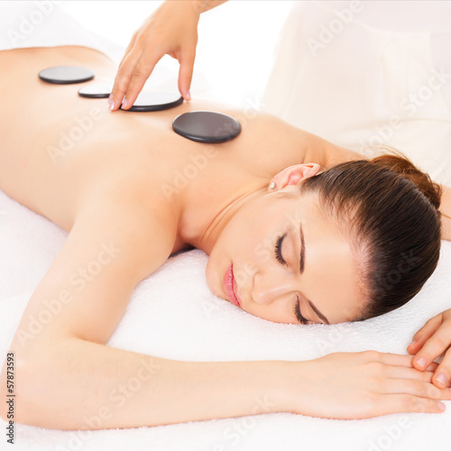 Woman having hot stone massage in spa salon.