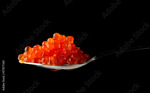 Red caviar in metal spoon isolated on black