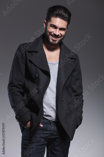 young man with long beard in an overcoat smiling