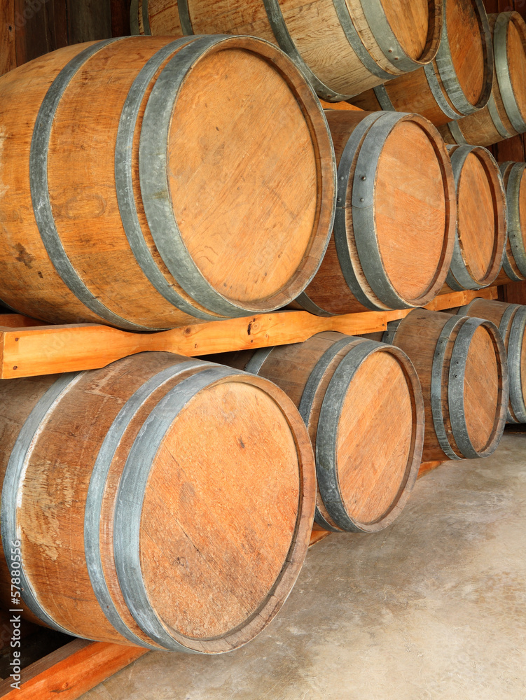 Stack of round wooden wine barrels in cellar shelf.