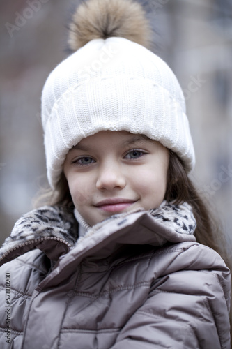 Little girl in a white knitted hat autumn