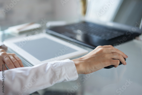 Woman's hand using cordless mouse on glass table