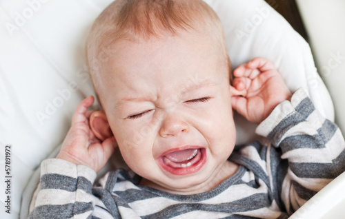 cute little boy crying holding his ear