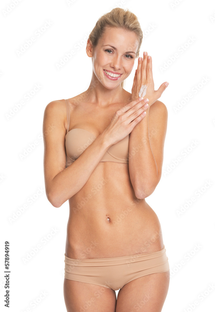 Happy young woman in lingerie applying creme on hand Happy young woman in lingerie applying creme on hand