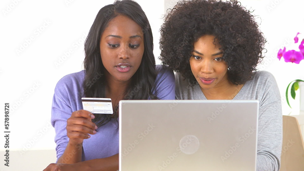 Two African American friends making online purchase with laptop Two African American friends making online purchase with laptop