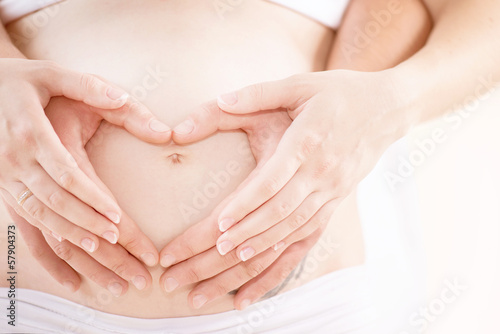 Couple Expecting Baby. Pregnant Belly with fingers Heart symbol
