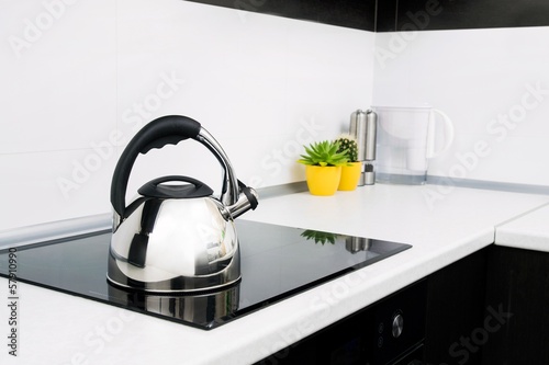 Steel kettle in modern kitchen with induction stove