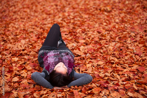 Photography Woman is relaxing on red leaves in autumn