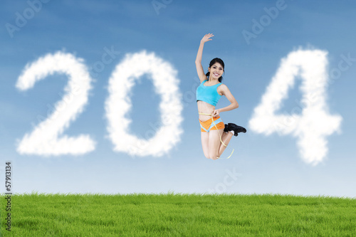 Athletic woman jumping with shaped clouds of 2014