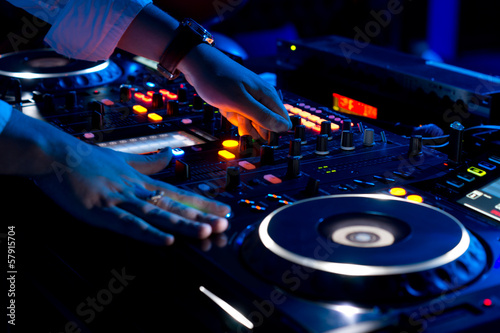 Hands of a DJ mixing music at a disco