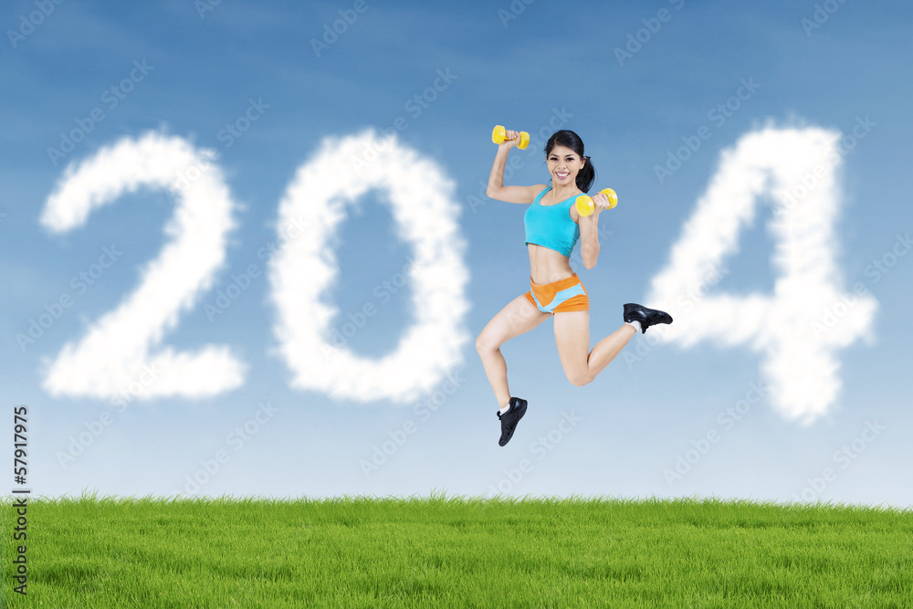 Fitness woman jumping with shaped clouds of 2014 Fitness woman jumping with shaped clouds of 2014
