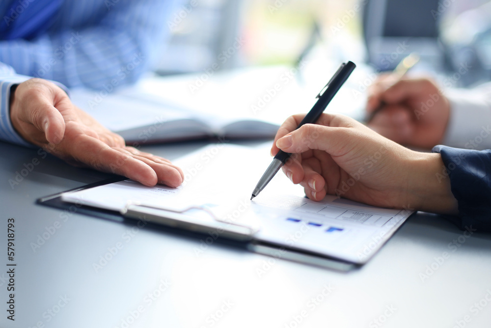 Unrecognizable business person analyzing graphs and taking notes Unrecognizable business person analyzing graphs and taking notes