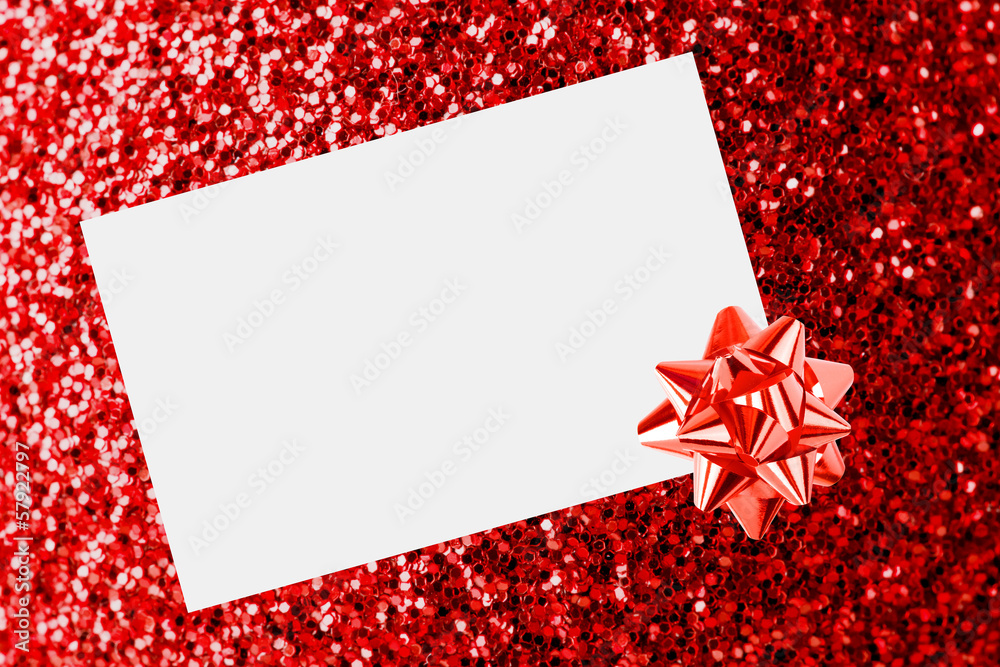 Christmas sheet of paper with bow on red defocused background Christmas sheet of paper with bow on red defocused background