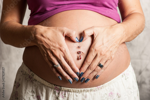 Woman making heart with hands over baby tummy