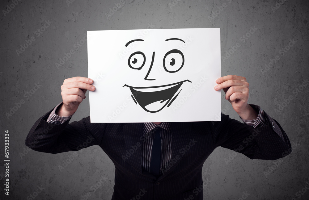 Businessman holding a cardboard with smiley face on it in front Businessman holding a cardboard with smiley face on it in front
