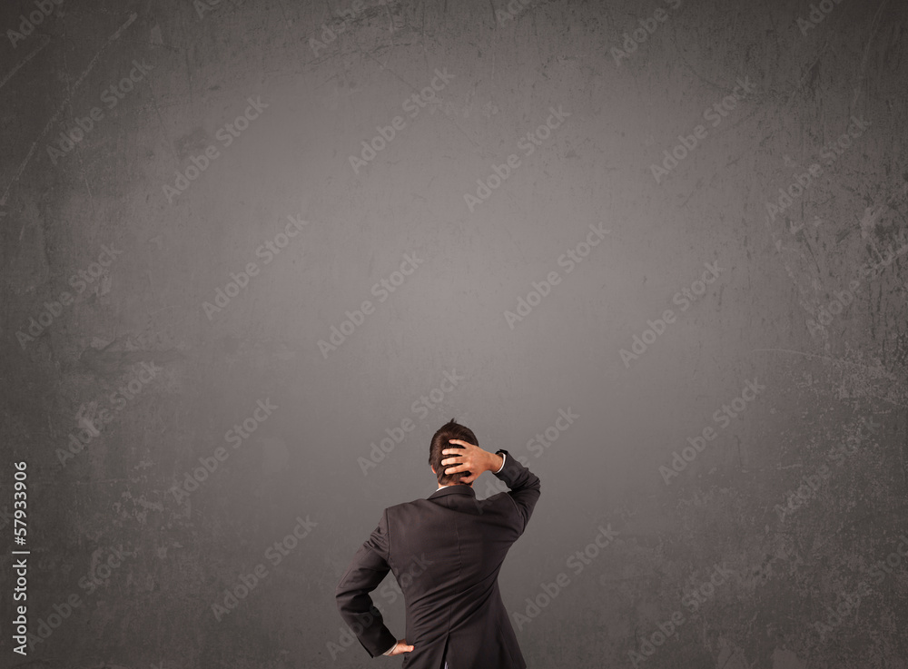 Businessman standing in front of an empty wall Businessman standing in front of an empty wall