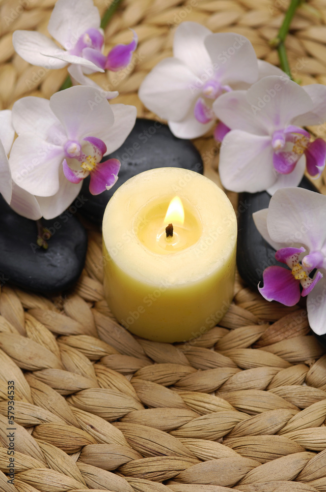 Candle and stones with orchid with stones on mat