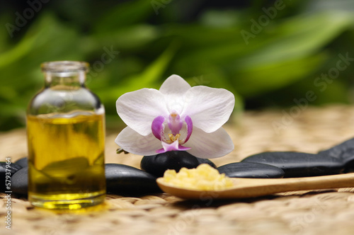Spoon of spa salt with orchid and stones with on wicker mat
