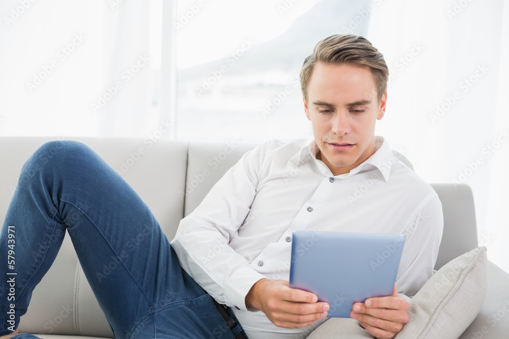Casual young man using digital tablet on sofa Casual young man using digital tablet on sofa
