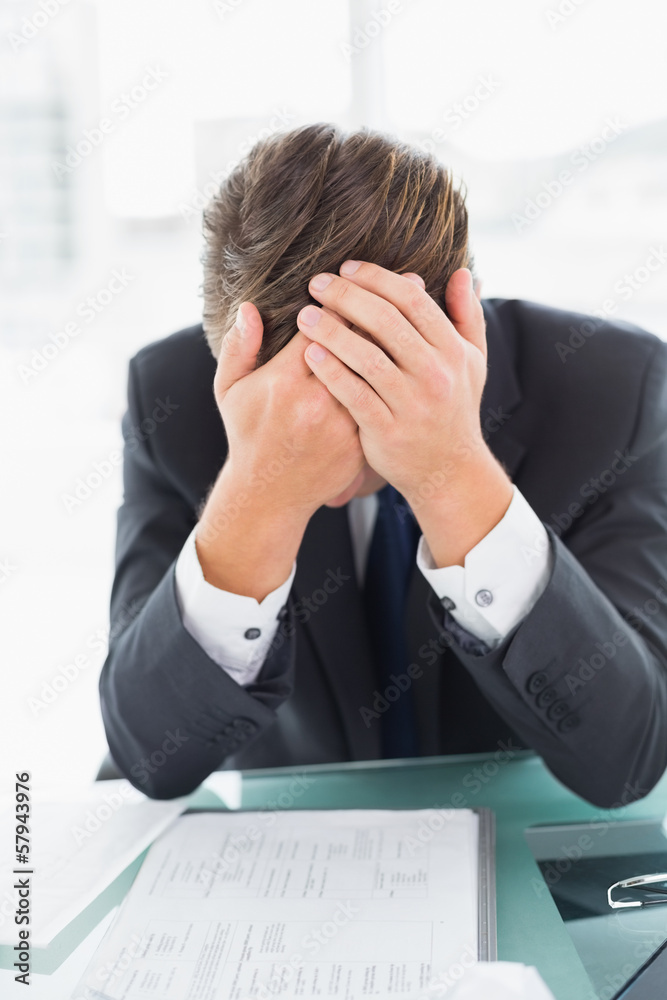 Worried businessman with head in hands at office desk Worried businessman with head in hands at office desk