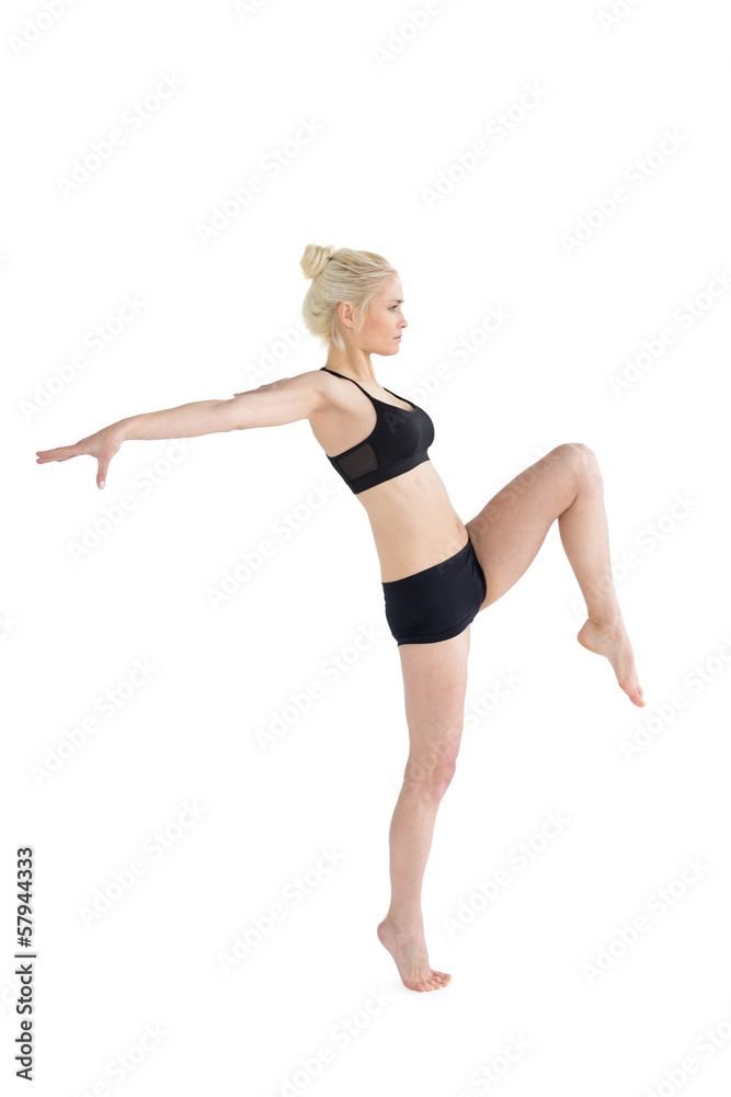 Sporty woman balancing on one leg while stretching out hands Sporty woman balancing on one leg while stretching out hands