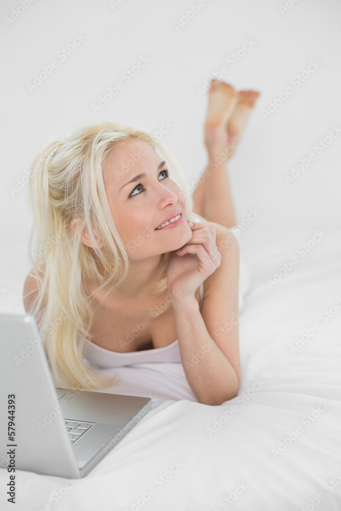 Thoughtful casual relaxed blond with laptop in bed Thoughtful casual relaxed blond with laptop in bed