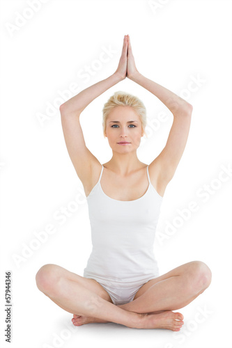 Toned young woman sitting with joined hands over head