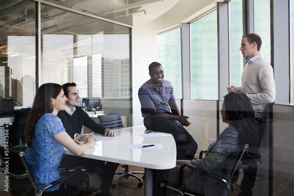 Five business people sitting at a conference table and discussing during a business meeting Five business people sitting at a conference table and discussing during a business meeting
