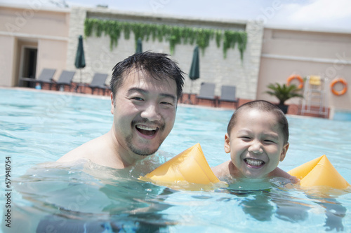 Portrait of smiling father and son in the pool on vacation