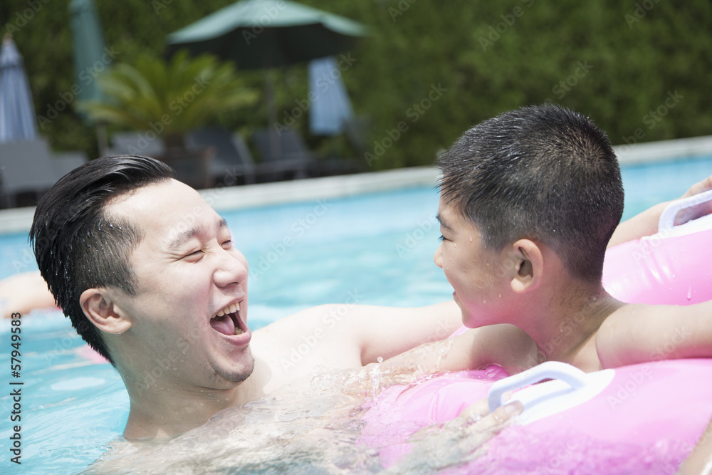 Smiling father and son playing in the pool Smiling father and son playing in the pool