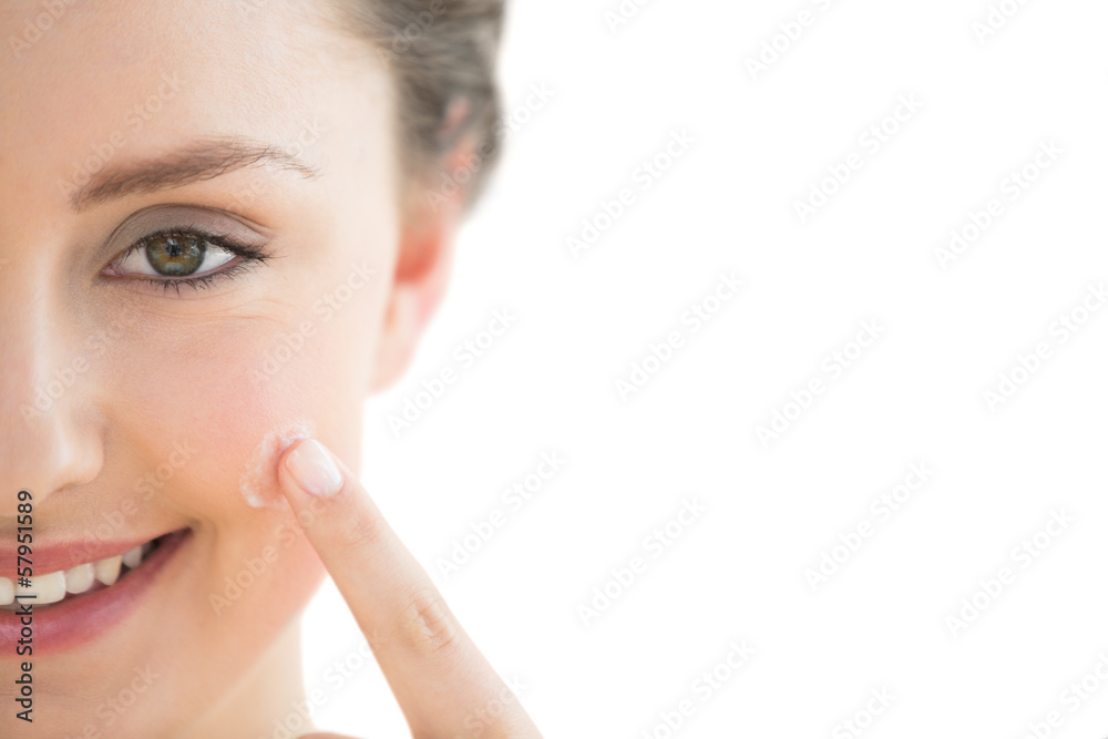 Beautiful young woman applying cream to her face Beautiful young woman applying cream to her face