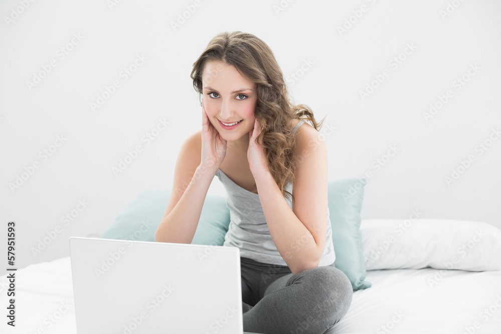 Smiling casual brunette with laptop in bed Smiling casual brunette with laptop in bed