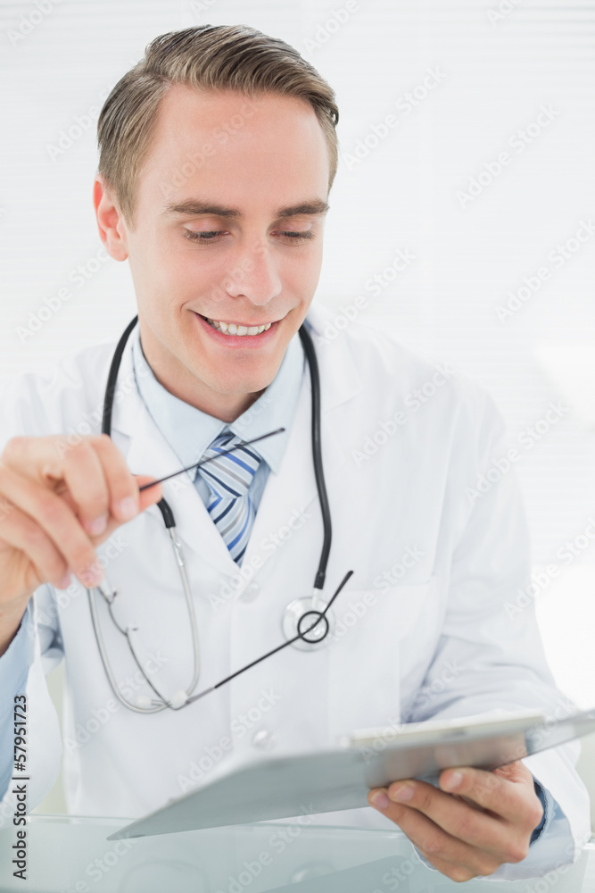 Smiling male doctor looking at digital tablet Smiling male doctor looking at digital tablet