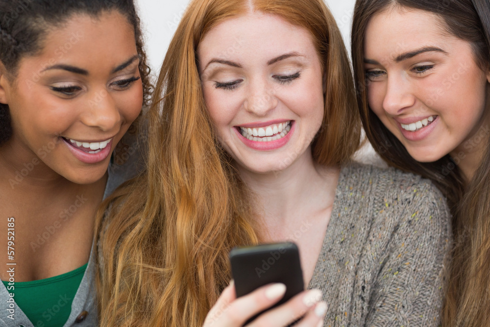 Close up of cheerful friends looking at mobile phone together Close up of cheerful friends looking at mobile phone together