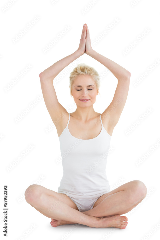 Toned young woman sitting with joined hands over head Toned young woman sitting with joined hands over head