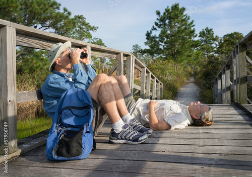 Seniors birdwatching and relaxing on old wooden footbridge photo