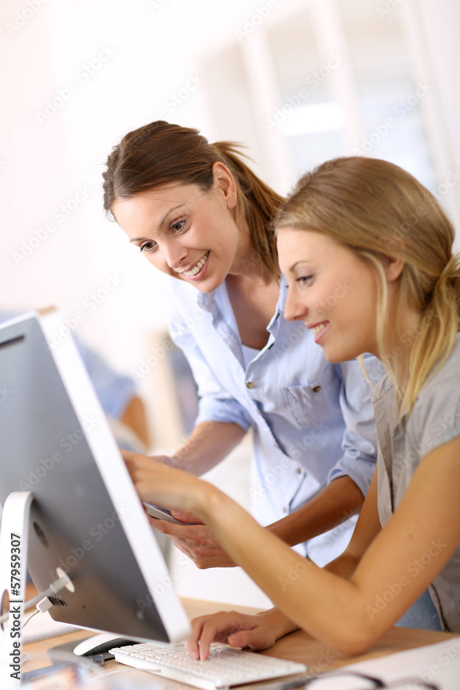 Young women in office working together on desktop Young women in office working together on desktop